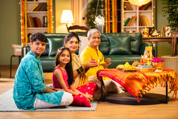 Indian family celebrating Ganesh Chaturthi, performing puja with traditional rituals and offerings