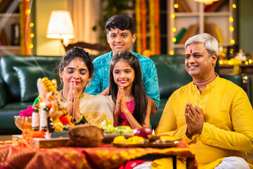 Indian family celebrating Ganesh Chaturthi, performing puja with traditional rituals and offerings