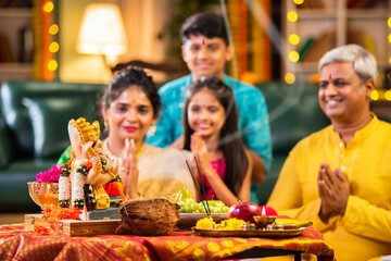 Indian family celebrating Ganesh Chaturthi, performing puja with traditional rituals and offerings