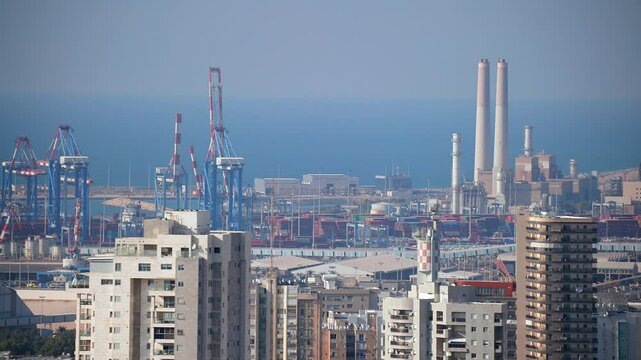 A city skyline with a large body of water in the background. Ashdod in Israel. View on the port. The buildings are tall and the city appears to be bustling with activity. ships are sailing. High