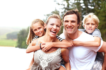 Family, piggyback and laugh in outdoor portrait, lake holiday and bonding together on weekend trip. Parents, children and carrying kids for support on vacation, love and smile for fun by river water