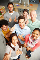 Fototapeta premium Excited, business people and portrait with thumbs up above for good job, well done or positive feedback at office. Top view or group of happy employees with smile, like emoji or yes sign for success