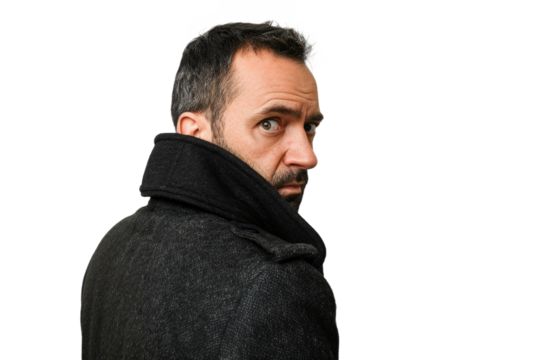 Portrait of a man with an anxious look checking over his shoulder, symbolizing paranoia, on a white backdrop.