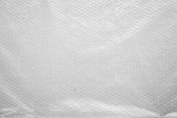 A close-up of a wrinkled plastic and foil texture, featuring crumpled patterns and a mix of silver and black hues. The grunge element adds an abstract, reflective quality to the material.