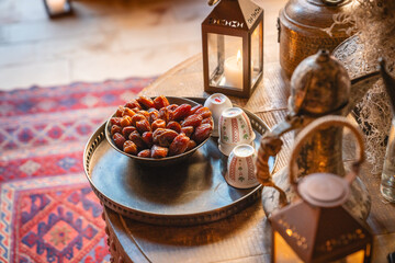Traditionelles Willkommen auf Arabisch mit Datteln, tablechern und Tee auf Tisch mit Kerze in Glas auf einem Teppich im Inneren schön dekoriert