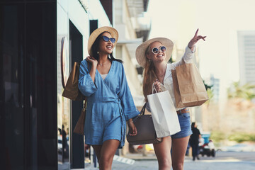 Pointing, friends and happy women with shopping bags in city for fashion sunglasses, discount or...
