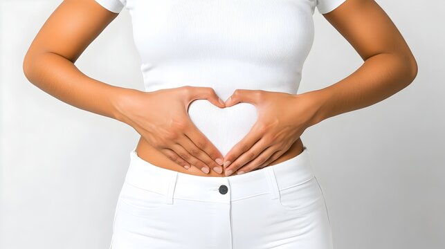 Closeup of woman making heart shape with hands over abdomen emphasizing digestive health and self care