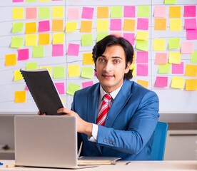 Young handsome employee with many conflicting priorities