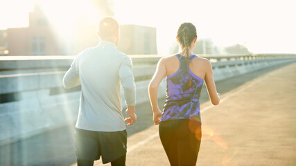 People, couple and running on road for fitness with training, support and care in California. Back, exercise and workout with jogging for health or wellness and wellbeing in sportswear in lens flare © Beak Joint/peopleimages.com