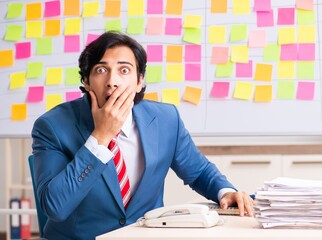 Young handsome employee with many conflicting priorities