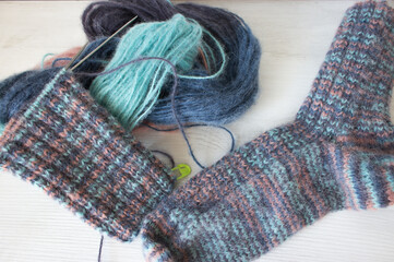 Colourful yarn ball with knitted sock and knitting needles. Alpaca and wool threads with beautiful knitting pattern. Woven crochet close up. Knitting hobby. Knitwear concept. Needlework background. 