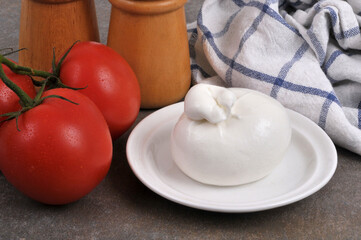 Burrata dans une soucoupe à côté de tomates fraîches en gros plan