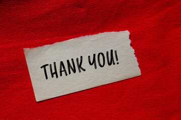 Thank you message written on ripped torn paper piece with red background. Conceptual thank you...