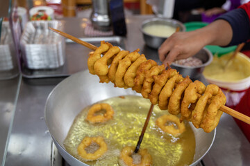 A woman is cooking picarones in a pan