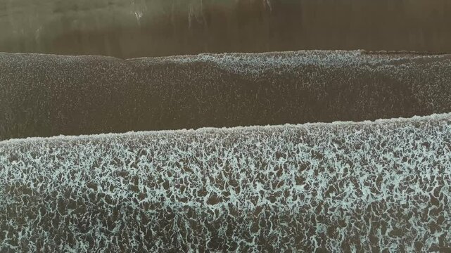 Barrido de olas blancas que crean un efecto de s&aacute;banas en la arena que es captado por un drone en 4k. Este espect&aacute;culo natural se crea desde las alturas y toca la arena amarilla, azul y atardeceres.