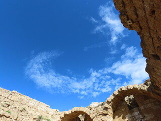Beautiful view from the ruins of an ancient city in Caesarea in Israel to a blue sky and a crescent of white clouds. An interesting journey through historical sights.