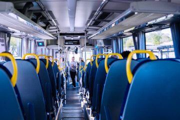 A modern bus interior features empty seats with yellow handles for visibility and accessibility