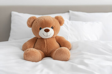 A cute brown teddy bear sitting on a cozy bed, surrounded by soft white pillows. Perfect for children's rooms or playful decor.