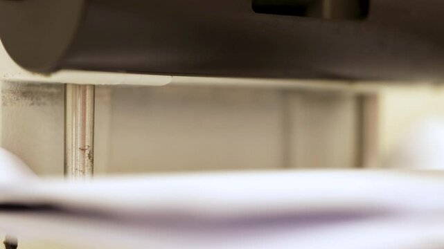 4K video macro detail of a paper punching machine perforating some sheets