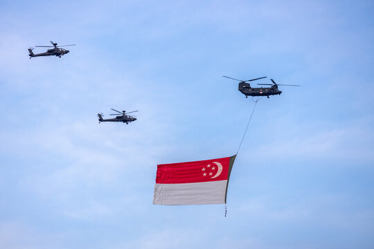 Apache helicopter flying a giant Singapore flag in the sky