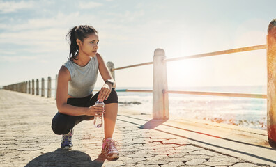 Water, fitness and woman outdoor for relax, break or rest for wellness at beach promenade. Bottle, runner or tired athlete with liquid for hydration after exercise, sport or thinking of healthy body