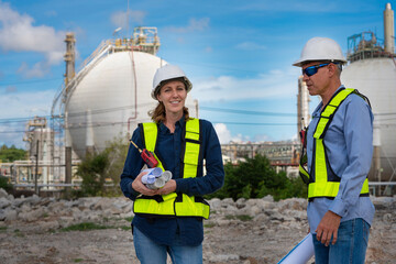 Team Petroleum chemical engineer discussion about blueprint drawings inside Oil Refinery Gas Chemical site. Senior Engineer wearing safety jacket and PPE working about Petro Chemical plant