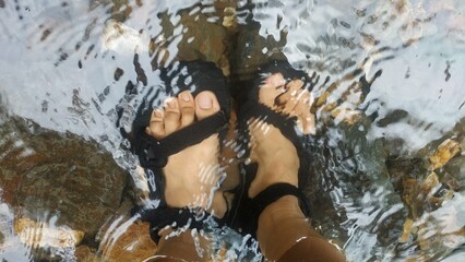 Feet in Sandals Submerged in Clear Stream