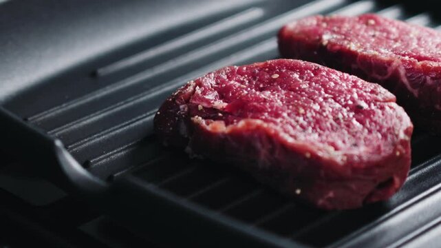 Slow motion slide shot of preparing steak filet mignon on a grill pan