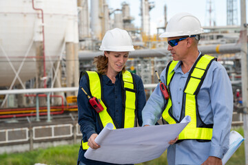 Team Petroleum chemical engineer discussion about blueprint drawings inside Oil Refinery Gas Chemical site. Senior Engineer wearing safety jacket and PPE working about Petro Chemical plant