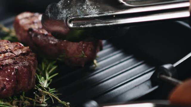 Slow motion slide shot of taking away steak filet mignon on a grill pan