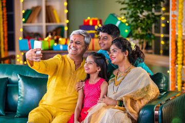 Indian family taking a festive Diwali selfie with while sitting on a sofa, capturing joyful moments