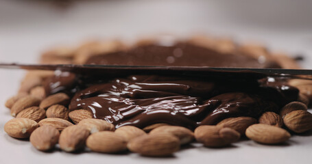 closeup spreading chocolate over roasted almonds