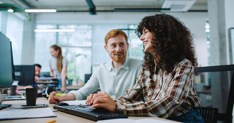 Camera moving closer to two Caucasian colleagues working side by side in modern office. Woman...