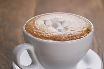 fresh cappuccino with marshmallow on wood oak table