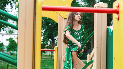 Obraz premium Cute child girl having fun on a playground outdoors in summer in sunny weather. Sport activities for kids.