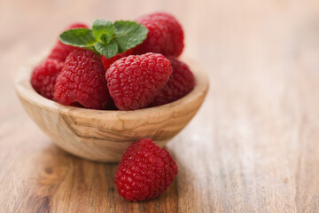 fresh raspberries in wood bowl on table with copy space