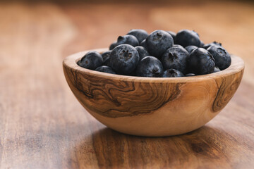 Fresh blueberries in wood bowl on table slightly toned