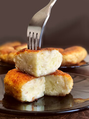 A cut fried potato is lying on a plate with a fork