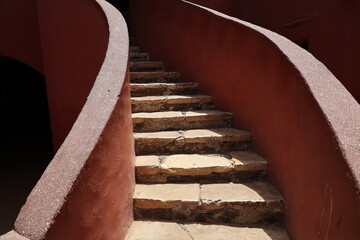 Vue d'un détail de l'escalier de couleur orangée de la maison des esclaves de l'île de Gorée au Sénégal. Rampe de forme incurvée. Architecture coloniale. Bâtiment rénové et coloré. Avril 2024.