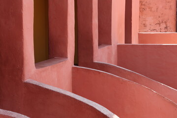 Vue d'un détail de l'escalier de couleur orangée de la maison des esclaves de l'île de Gorée au Sénégal. Rampe de forme incurvée. Architecture coloniale. Bâtiment rénové et coloré. Avril 2024.