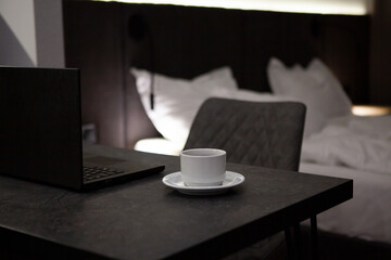 Hotel room with bed and comfort zone for work with laptop. Black furniture in interior design 