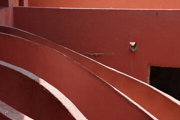 Vue d'un détail de l'escalier de couleur orangée de la maison des esclaves de l'île de Gorée au Sénégal. Rampe de forme incurvée. Architecture coloniale. Bâtiment rénové et coloré. Avril 2024.