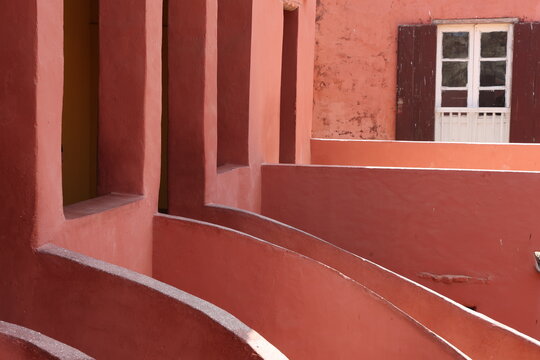 Vue d'un d&eacute;tail de l'escalier de couleur orang&eacute;e de la maison des esclaves de l'&icirc;le de Gor&eacute;e au S&eacute;n&eacute;gal. Rampe de forme incurv&eacute;e. Architecture coloniale. B&acirc;timent r&eacute;nov&eacute; et color&eacute;. Avril 2024.