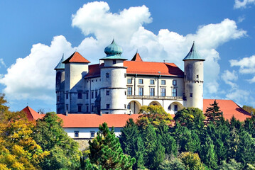 Castle Nowy Wisnicz in Poland in sunny autumn day on a background of blue sky with white clouds