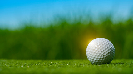 Golf ball on green grass in the evening golf course with sunshine background.