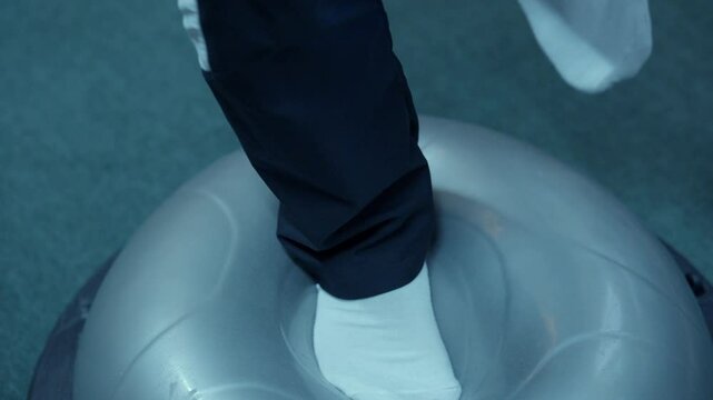 Close up of a man standing on a bosu ball doing rehabilitation exercises for an injury, physiotherapy and medical assistance.