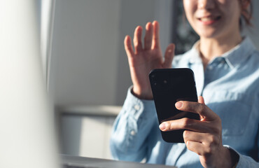 Happy young asian woman waving hand using smartphone app enjoying online virtual chat video call with friends on mobile chat virtual meeting, online working from home
