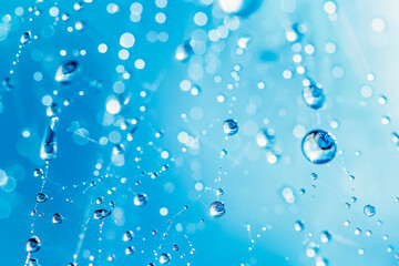Closeup of spiderweb covered in dew droplets, with a vibrant blue bokeh background, creating a dreamy and ethereal effect