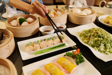 Close-up of woman eating rolls with sticks in the restaurant