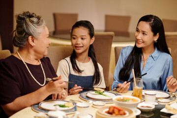 Family of three sitting at dining table and talking at dinner at the restaurant